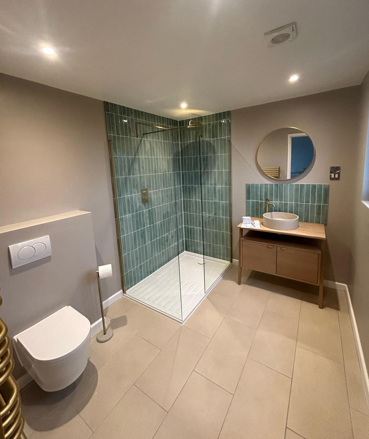 Loft conversion en-suite with walk-in shower. Gold radiator and taps. Vertical green tiles used for shower and splashback.