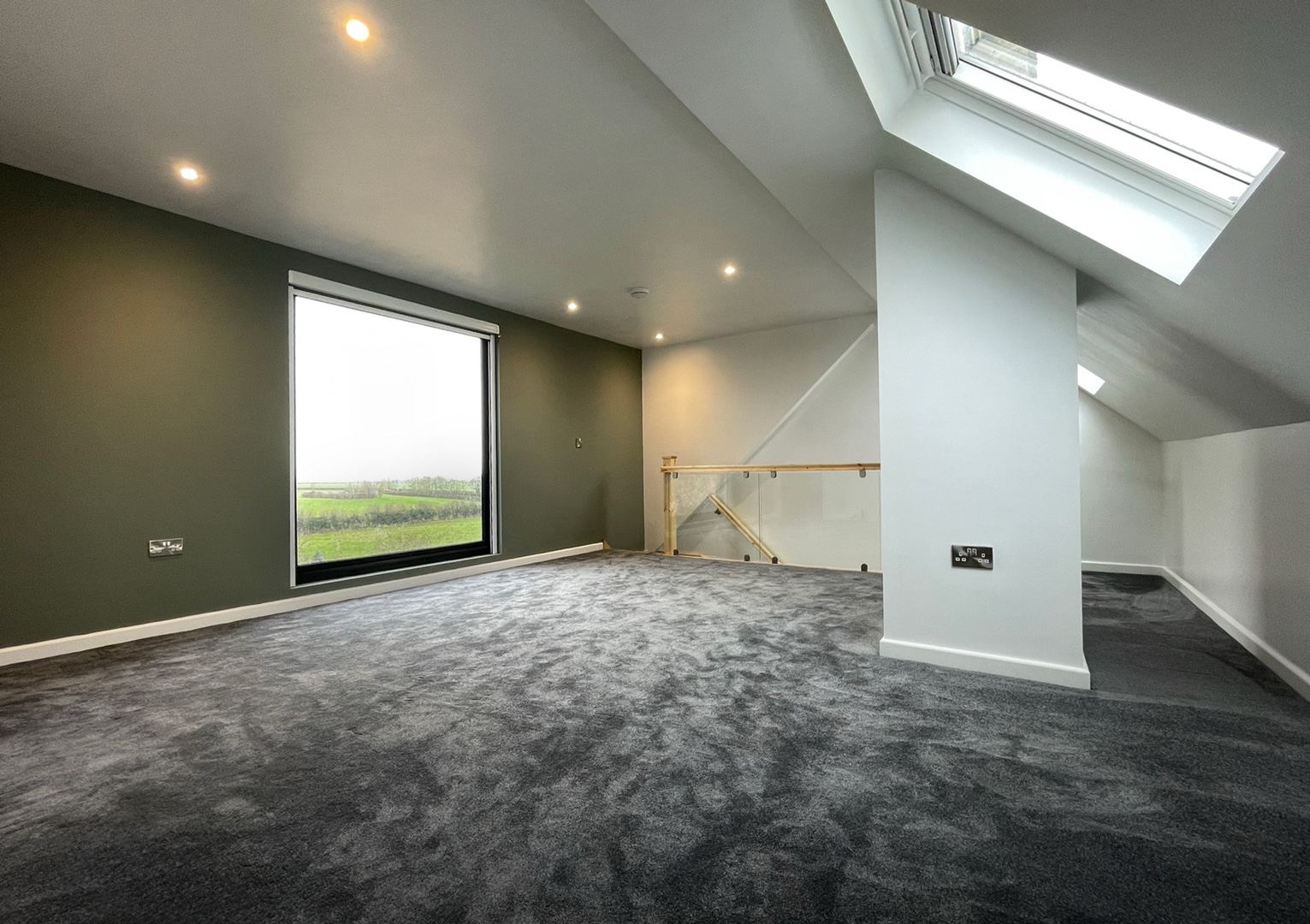 Spacious loft conversion in Buckinghamshire by J&T Herbert Lofts. Velxux roof light and Residence Collection R7 modern full-height window with anthractir grey frames.