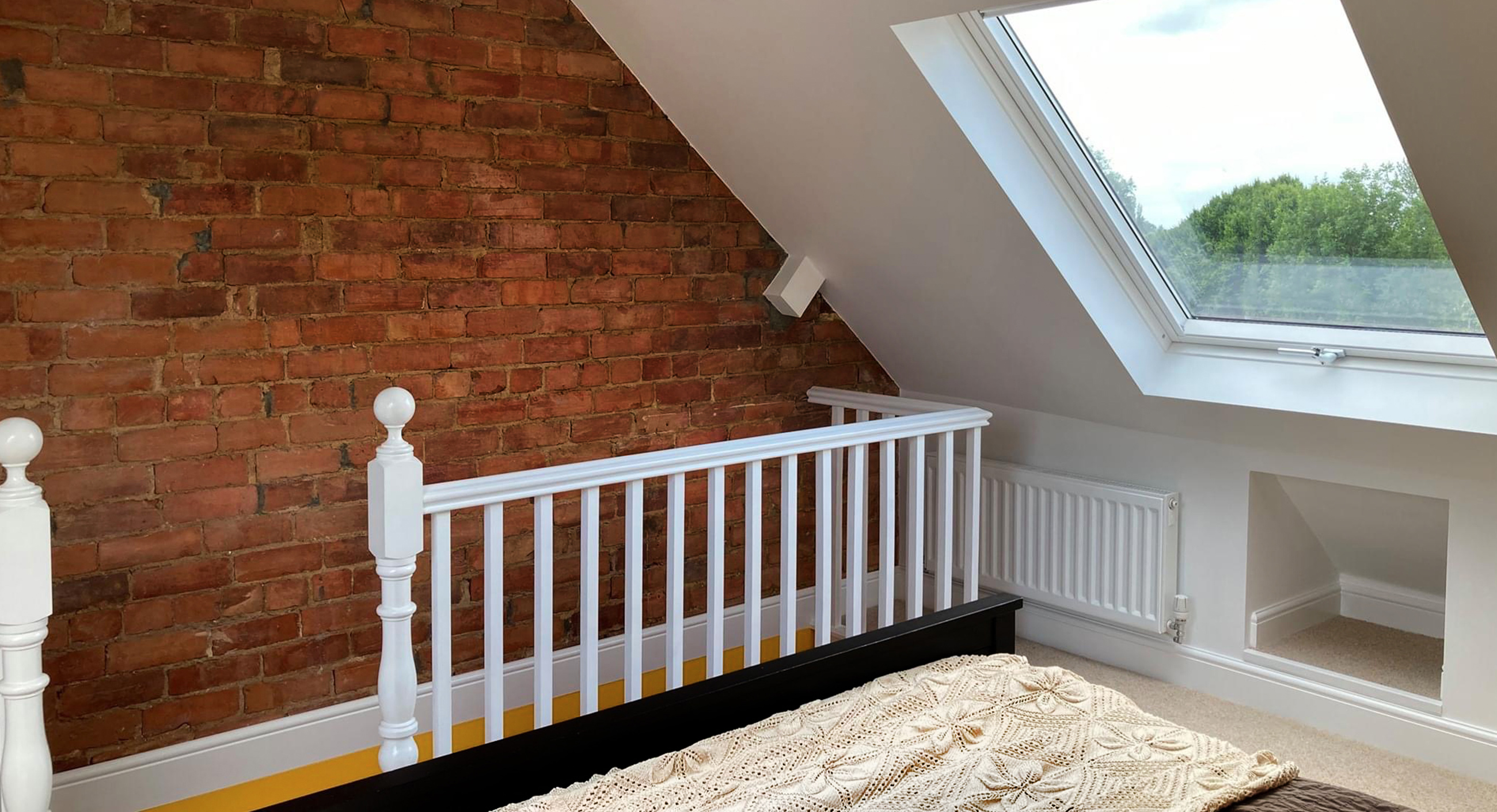 Loft conversion with bare brick wall and Velux window